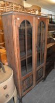AN OAK NARROW BOOKCASE WITH TWO GLAZED DOORS