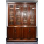 EARLY TWENTIETH CENTURY BROWN STAINED PITCH PINE FOUR DOOR BOOKCASE, the moulded cornice above two