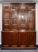 EARLY TWENTIETH CENTURY BROWN STAINED PITCH PINE FOUR DOOR BOOKCASE, the moulded cornice above two