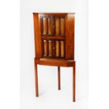 EARLY TWENTIETH CENTURY FIGURED WALNUT CORNER CABINET ON STAND, the upper section with two pairs