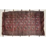 SEMI-ANTIQUE TURKOMAN BOKHARA RUG with three rows of guls on a wine red field, multiple narrow