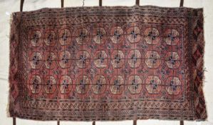 SEMI-ANTIQUE TURKOMAN BOKHARA RUG with three rows of guls on a wine red field, multiple narrow