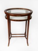 EDWARDIAN STYLE LINE INLAID MAHOGANY BIJOUTERIE DISPLAY TABLE WITH GILT METAL MOUNTS, of oval form