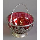 CRANBERRY GLASS SUGAR BASIN IN A SWING HANDLED WIRE PATTERN UNMARKED SILVER HOLDER, of cylindrical
