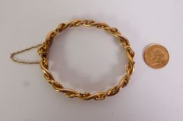LATE VICTORIAN HINGE OPENING BANGLE, of foliate engraved and plain twisted strands, unmarked, 5cm by