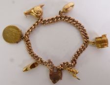 9CT GOLD CURB LINK CHARM BRACELET, with a 9ct gold padlock clasp and suspending five charms (one 9ct