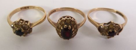 TWO 9ct GOLD AND DAISY CLUSTER RINGS, each with a centre red stone and surround of white stones