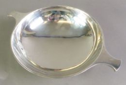 GEORGE VI PLAIN SILVER QUAICH SHAPED TWO HANDLED DISH, of shallow form with circular foot, 2 ½” (6.
