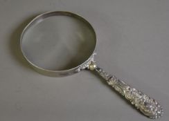 ‘GERMAN SILVER’ FRAMED LARGE MAGNIFYING GLASS WITH FOLIATE SCROLL EMBOSSED AND FILLED HANDLE,