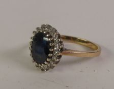 18CT GOLD SAPPHIRE AND DIAMOND CLUSTER RING, an oval-cut sapphire within a border of eight-cut