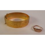 A METAL CORE FOLIATE ENGRAVED HINGE OPENING BANGLE, 6cm by 5cm; and A 9CT GOLD SIGNET RING (a/f),