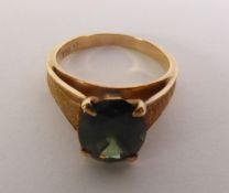 GREEN COLOUR CHANGE SAPPHIRE RING, an oval-cut sapphire to textured angular shoulders, marked ‘750’,