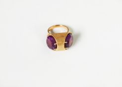 GOLD COLOURED METAL DRESS RING, the top with textured cylindrical setting, with two end amethysts,