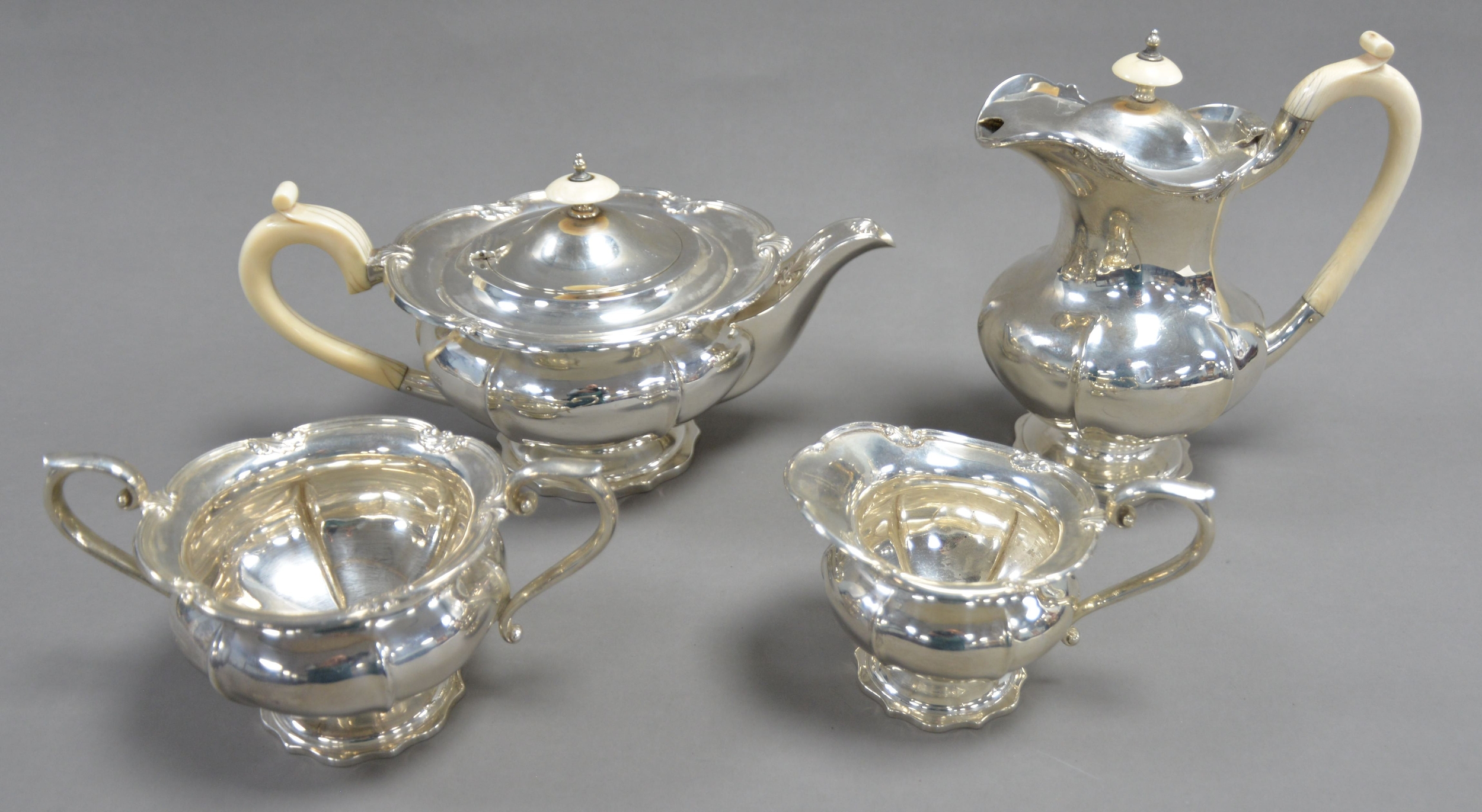 GEORGE V FOUR PIECE SILVER PEDESTAL TEASET WITH IVORY HANDLES BY WALKER & HALL, of lobated form with