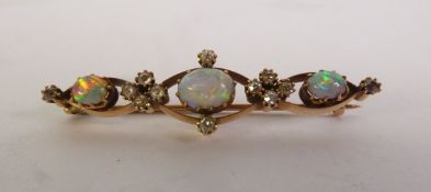 AN EARLY 20TH CENTURY OPAL AND DIAMOD BROOCH, three graduated oval opals spaced by groups of old-cut