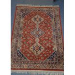 EASTERN RUG with red field with triple pole medallions of diamond shape, with zig zag borders, the