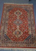 EASTERN RUG with red field with triple pole medallions of diamond shape, with zig zag borders, the
