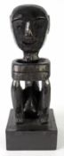 AFRICAN BLACK CARVED SOFTWOOD SEATED MALE FIGURE, 16 1/4in (41.2cm), on square plinth base, 19 1/2in