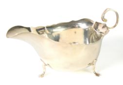 SILVER GEORGIAN STYLE SAUCE BOAT, with cyma edge, free scroll handle, raised on three trefoil