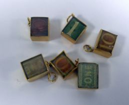SIX 9ct GOLD GLASS FRONTED BOX CHARMS, each containing a folded bank note, namely three one pound