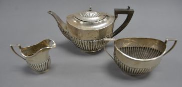 GEORGE V SILVER THREE PIECE TEASET, of oval, part fluted form with black angular scroll handles