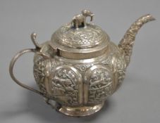 UNMARKED INDIAN EMBOSSED SILVER COLOURED METAL TEAPOT, of footed, globular form with cobra pattern