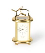 MODERN OVAL BRASS CASED CARRIAGE CLOCK, the Roman dial inscribed 'WOODFORD Est 1860', with key, 6 ¼"