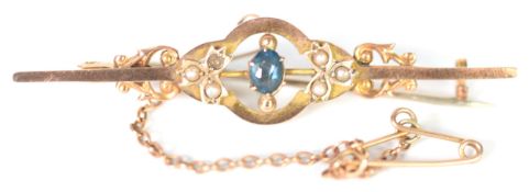 9ct GOLD BAR BROOCH, the circlet centre collet set with a small oval sapphire flanked by foliate