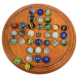 A 19th century treen birch solitaire board and glass marbles