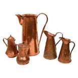 An Arts and Crafts hammered copper ewer and four other jugs