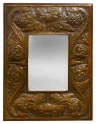 An Arts & Crafts repousse embossed copper and oak wall mirror