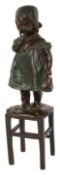 A bronze figure of a young girl standing on a stool