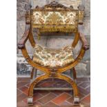 Heavily carved and upholstered x framed armchair. App. 89cm H x 59cm W x 39cm D Used condition,