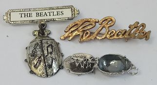Three pieces of original Beatles jewellery including Beatles Script Brooch, a Silver Beetles Charm
