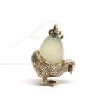 A small Faberge style silver chicken with ruby eyes holding a jade egg, mounted as a pendant, H. 3.