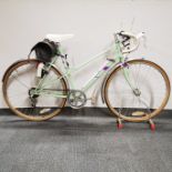 An Emmelle Emerald vintage women's road bicycle and stand with Shimano Tourney breaks and gears.