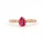 A rose gold on 925 silver ring set with a pear cut ruby and white topaz set shoulders, (O).