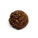 A Chinese carved walnut wood figure of a young dragon coiled around a ball, Dia. 6cm, D. 3.5cm.