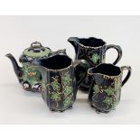 A set of three Victorian black ceramic graduated jugs with a similar hand-painted teapot, tallest H.