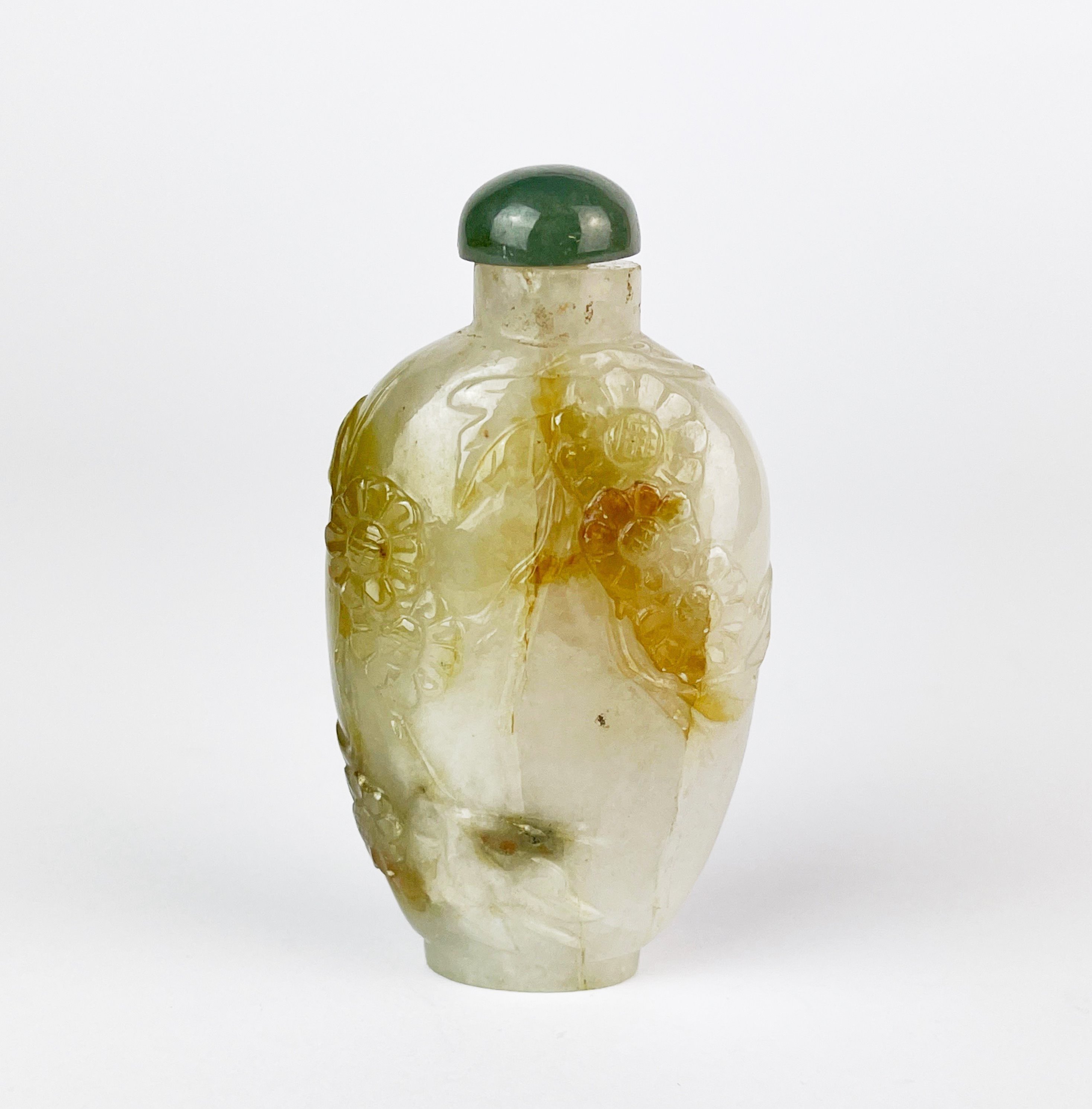 A Chinese carved mixed colour jade snuff bottle decorated with flowers and foliage, H. 7.5cm.