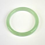 A pale green jade bangle, W. 1cm internal Dia. 6cm.