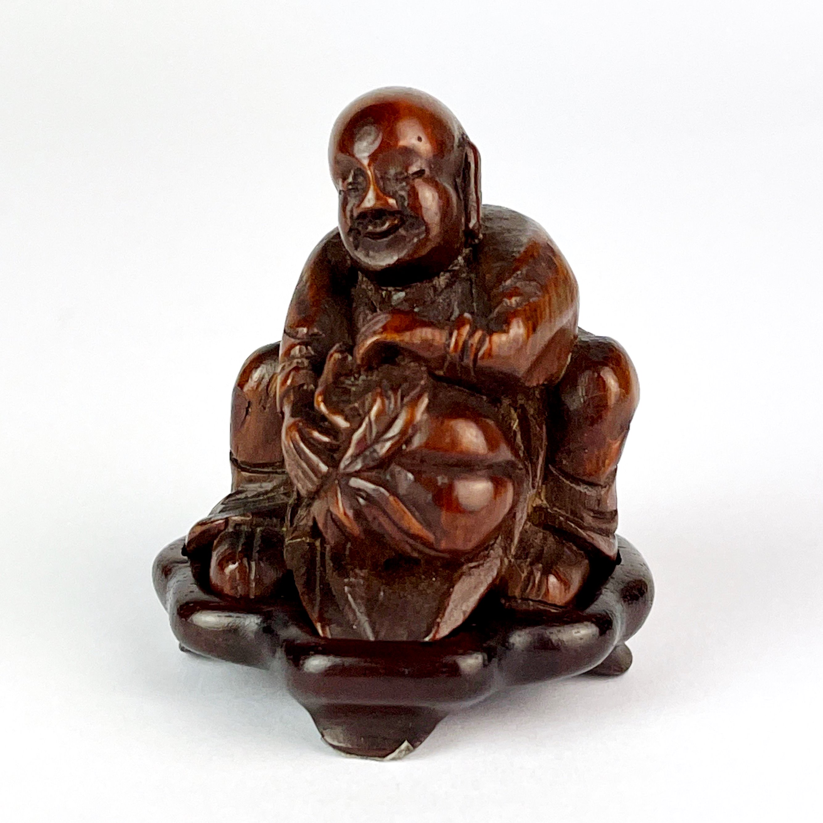 A finely carved Chinese bamboo figure of a man holding a peach with a carved wooden base, H. 5cm.