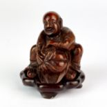 A finely carved Chinese bamboo figure of a man holding a peach with a carved wooden base, H. 5cm.