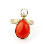 A white metal ring set with a large pear cabochon coral and a pearl, (R). Deep clean required.