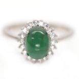 A 925 silver cluster ring set with a cabochon cut emerald surrounded by white stones, (P).