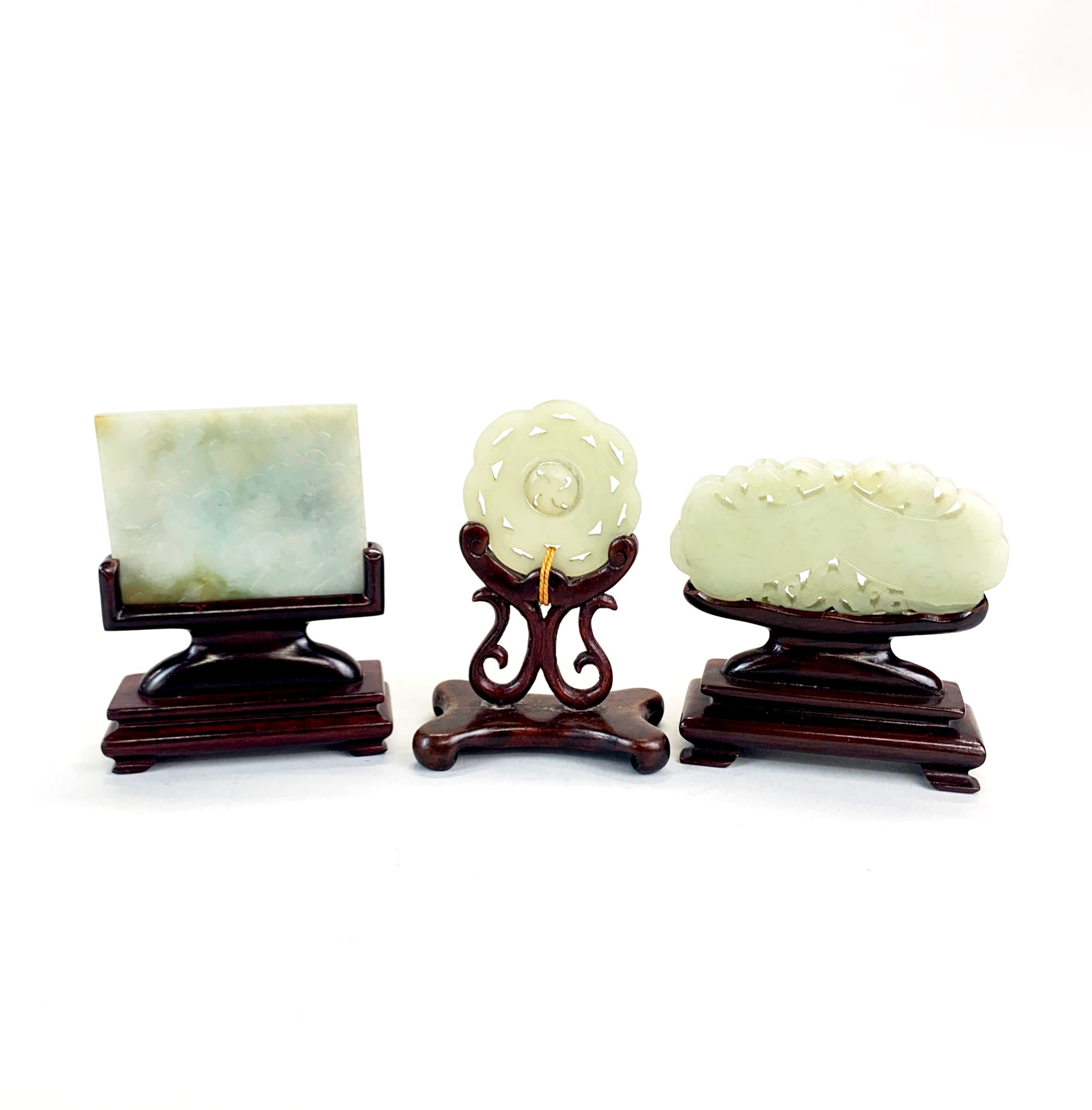 Three carved celedon jade items on carved wooden stands. H 11cms - Image 2 of 2