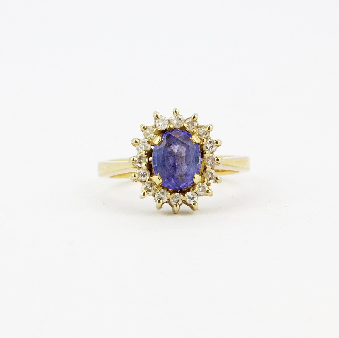 An 18ct yellow gold cluster ring set with an oval cut tanzanite surrounded by diamonds, tanzanite