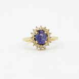 An 18ct yellow gold cluster ring set with an oval cut tanzanite surrounded by diamonds, tanzanite