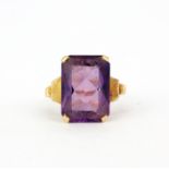 A yellow metal (tested minimum 9ct gold) ring set with a large baguette cut amethyst, amethyst