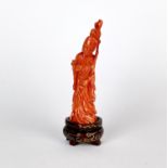 A fine Chinese carved coral figure on a carved wooden stand, H. 11.5cm.